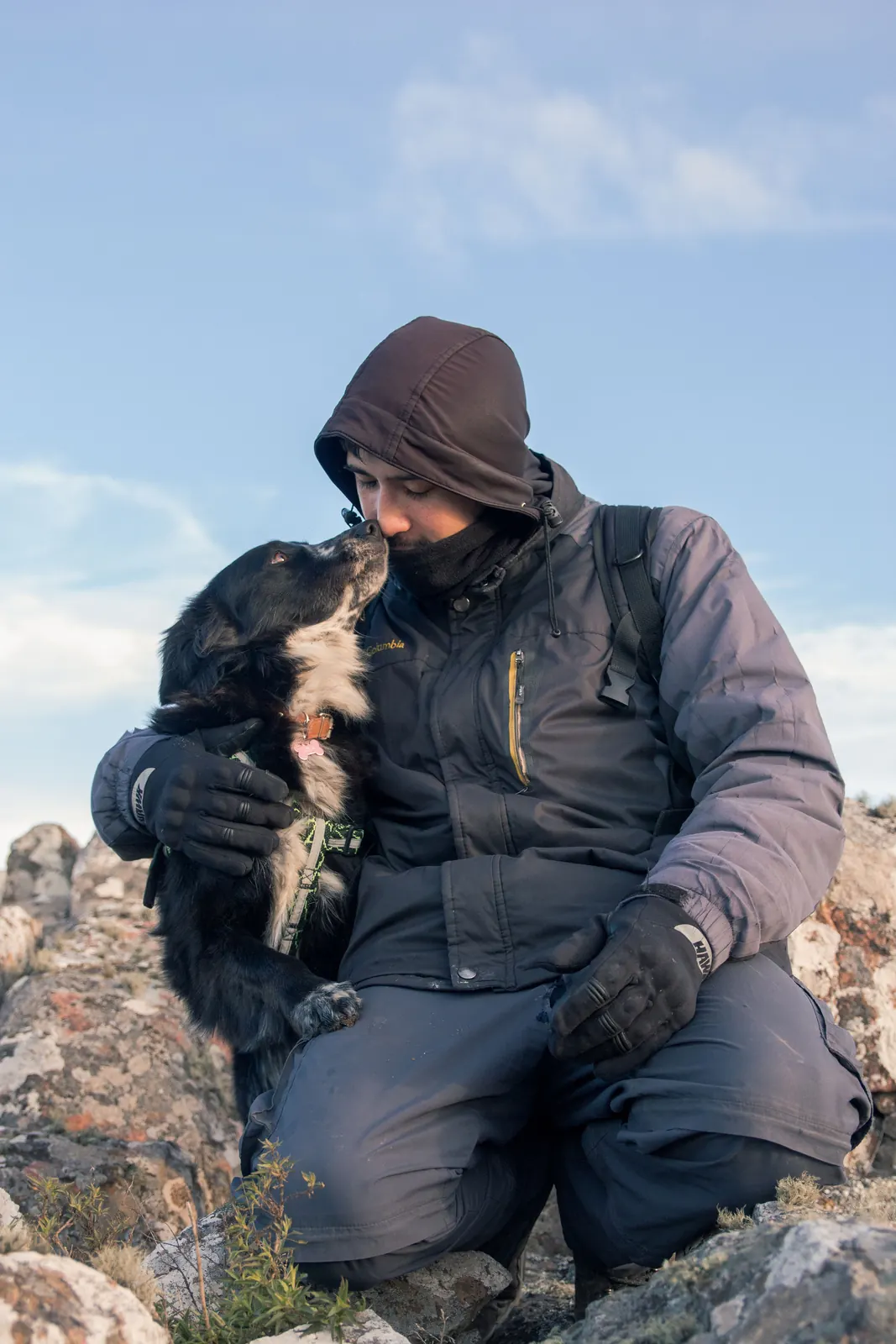 Hombre abrazando a su perro sobre las rocas