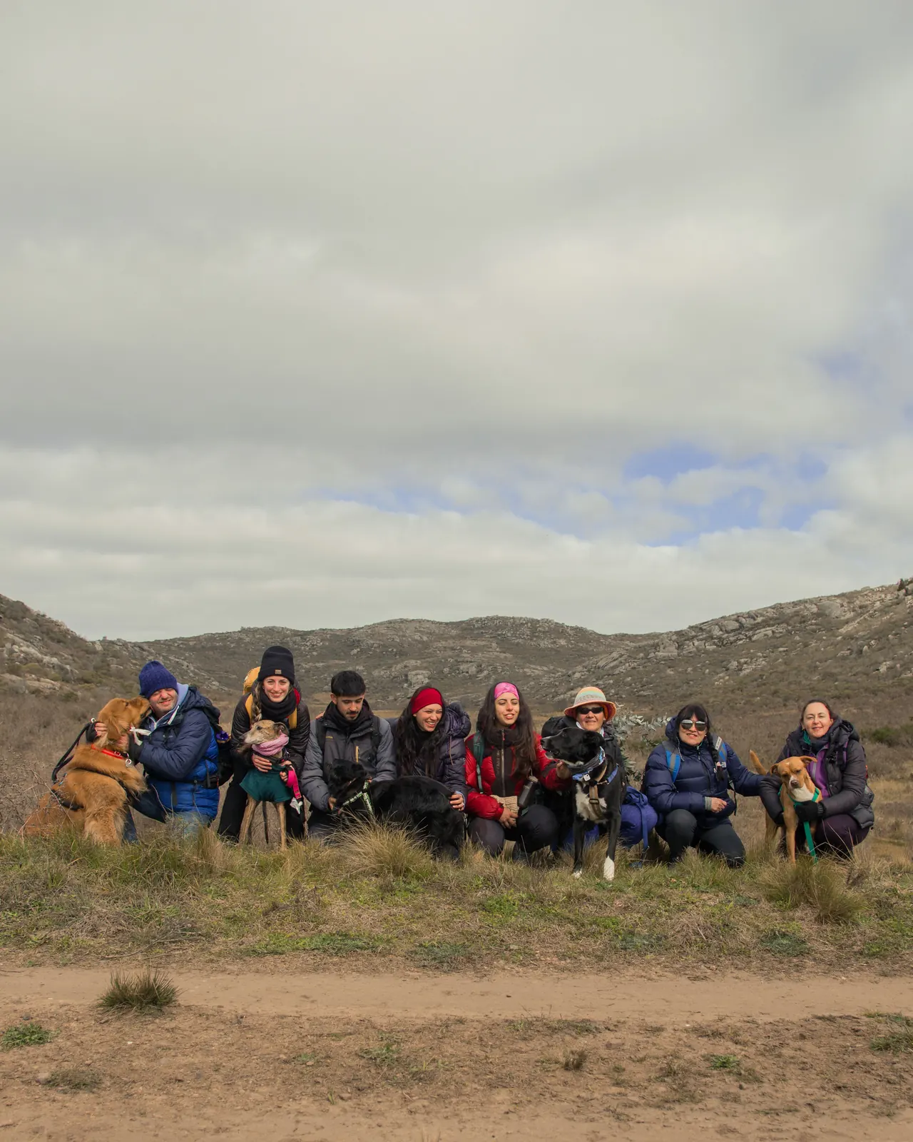 Grupo de caminantes y perros sentados frente a las sierras