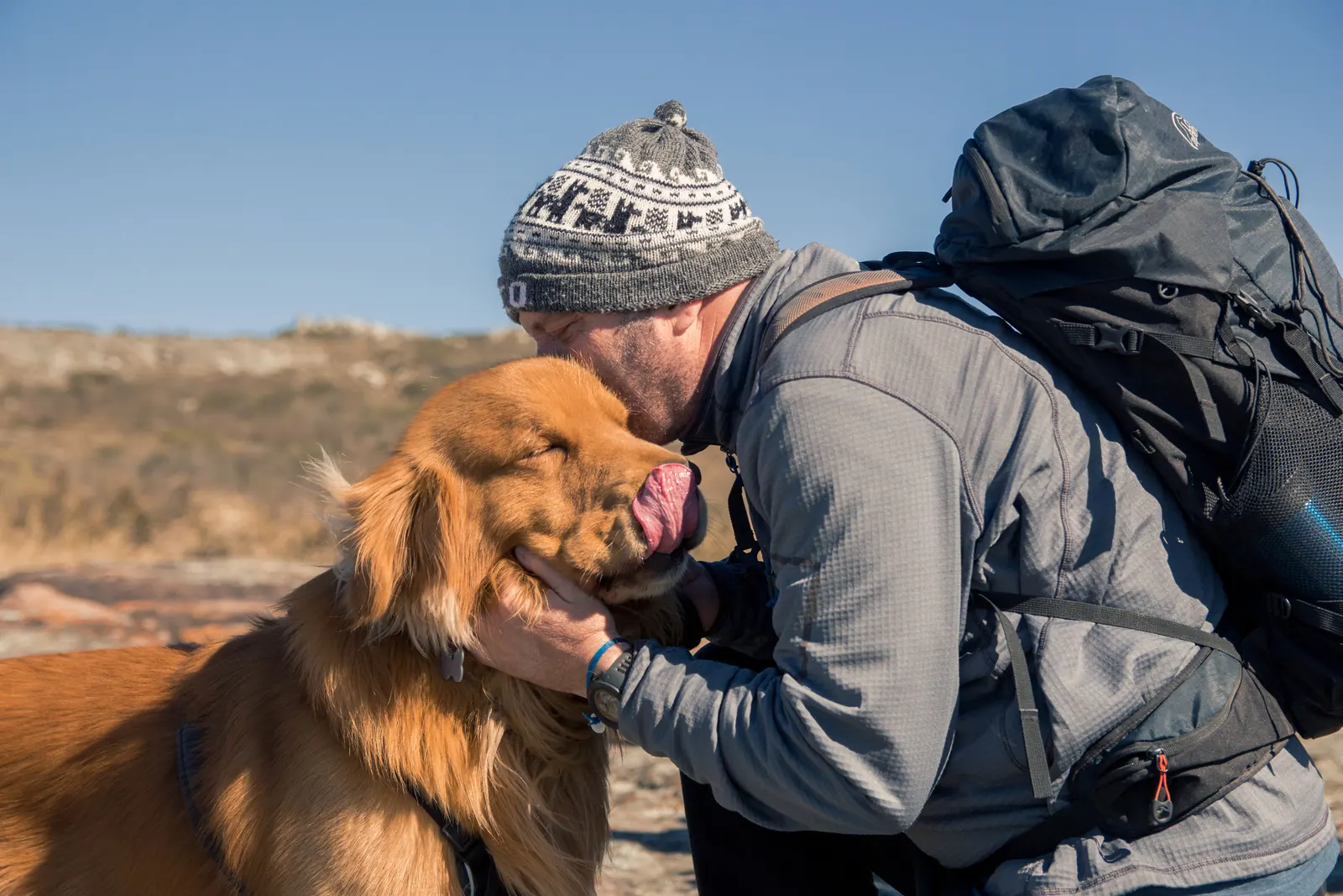 Caminante abrazando a su perro en la sierra
