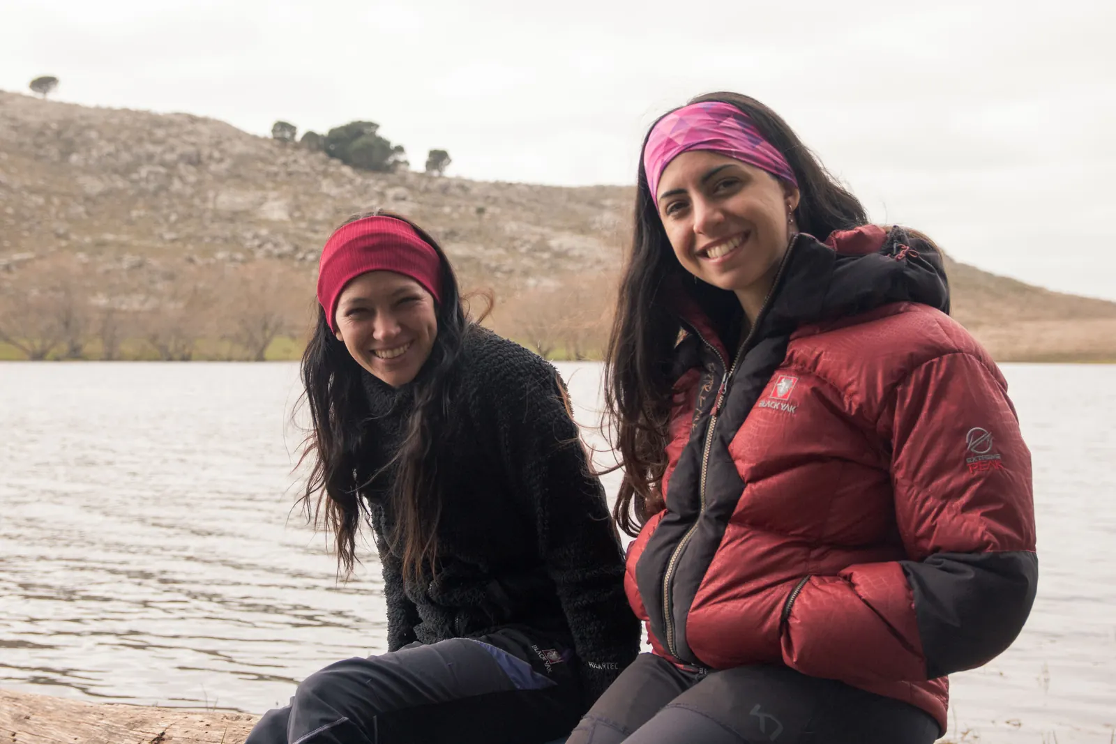 Dos amigas sentadas a orillas del agua en las sierras