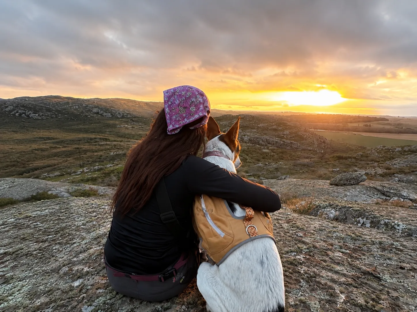 Florencia Marcos abrazada a su perra mirando el atardecer en las sierras